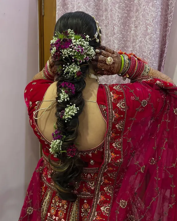 A stunning bridal braid adorned with fresh purple and white flowers. I teach my students how to securely incorporate flowers and other accessories into hairstyles.