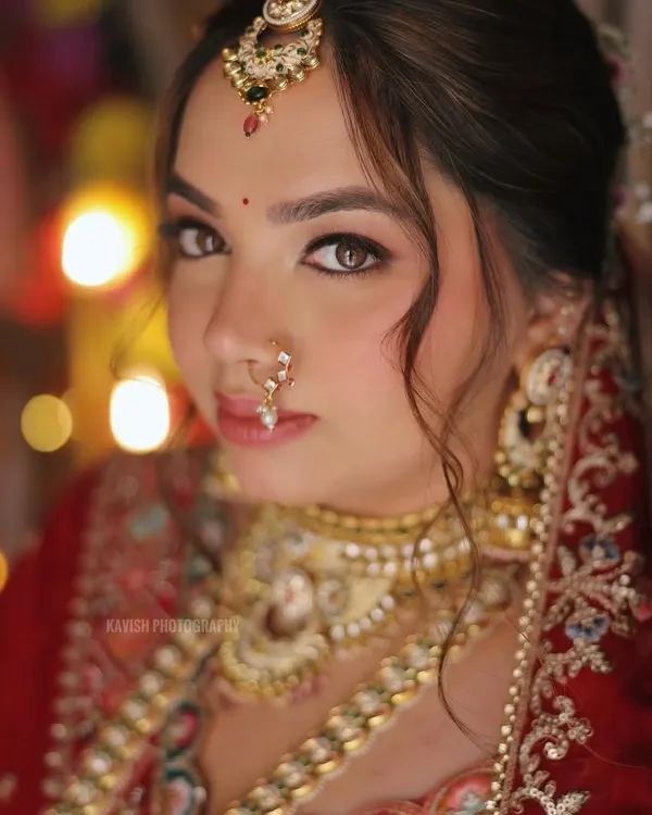 This is what bridal dreams are made of. This close-up captures the soft, radiant makeup that enhances her features without masking her beauty, complete with a traditional nath for that timeless elegance.