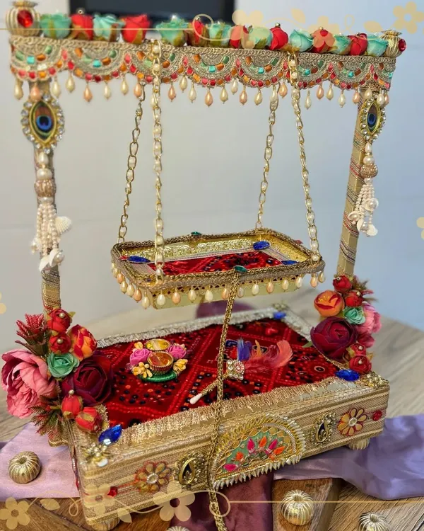 Celebrate the divine swing of Lord Krishna with our custom-made Janmashtami jhula. This piece is handcrafted with a beautiful red base, floral decorations, and pearl details, creating a perfect seat for Ladoo Gopal.