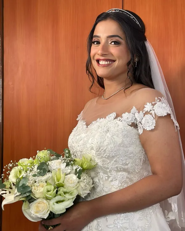 A vision in white. This bride is the picture of happiness, holding her bouquet with a radiant smile. Her makeup is soft and luminous, designed to look fresh and beautiful all day long.