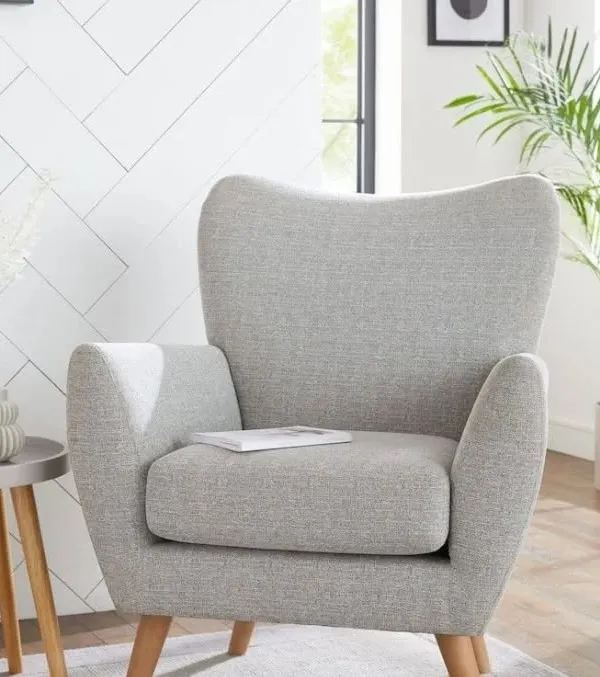 A completely customized armchair with a classic mid-century modern design. The light grey fabric and wooden legs make it a versatile piece for any living room.