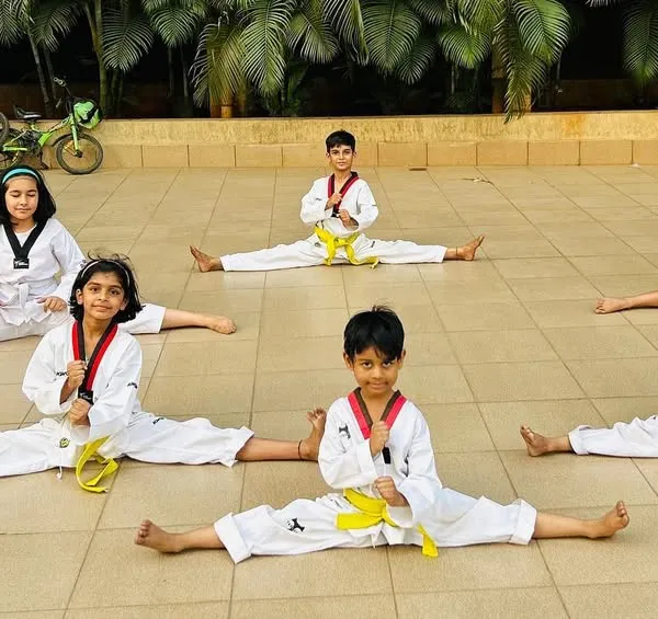The foundation of powerful kicks is flexibility. Here, our young students work on their splits, building the flexibility needed for high-level techniques.