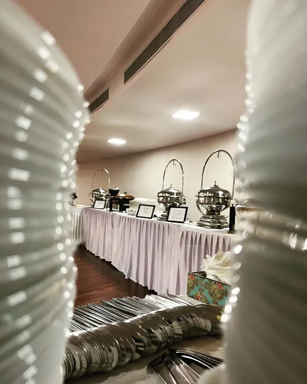 A view of a long, elegant buffet line ready for service, seen through a creative frame of stacked plates. This setup is perfect for large gatherings and weddings.