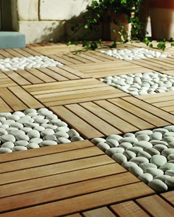 This image showcases an innovative flooring concept, combining the warmth of wooden deck tiles with the natural, textured look of white river pebbles. This method is great for creating visual interest and defining different areas.
