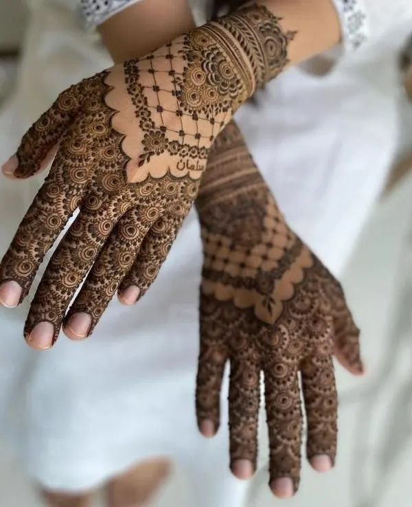 A showcase of extremely fine and detailed henna artistry. This design features delicate net patterns, or *jaali*, on the back of the hands, complemented by intricate mandalas and traditional motifs that flow down the fingers, all promising a deep, rich stain.
