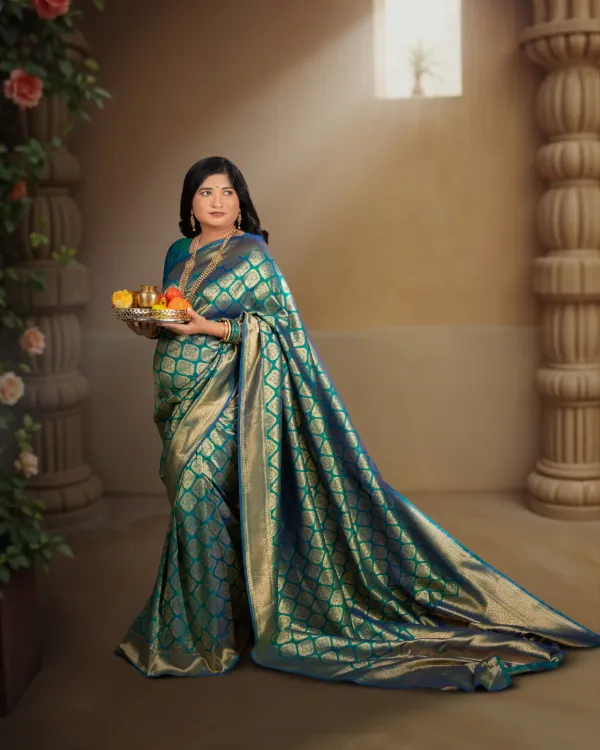 A timeless maternity portrait celebrating the grace of motherhood. This mother-to-be is captured in a classic studio setting, draped in an elegant teal and gold silk saree, creating a regal and artistic memory of her pregnancy.