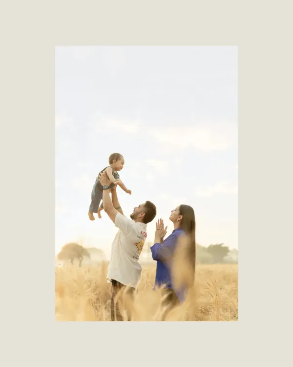 In a sun-drenched field of gold, a father lifts his child towards the sky, a moment of pure joy as the mother watches on. This is more than a family portrait; it is a tribute to the unwavering love that surrounds us, a love as nurturing and constant as the earth itself.