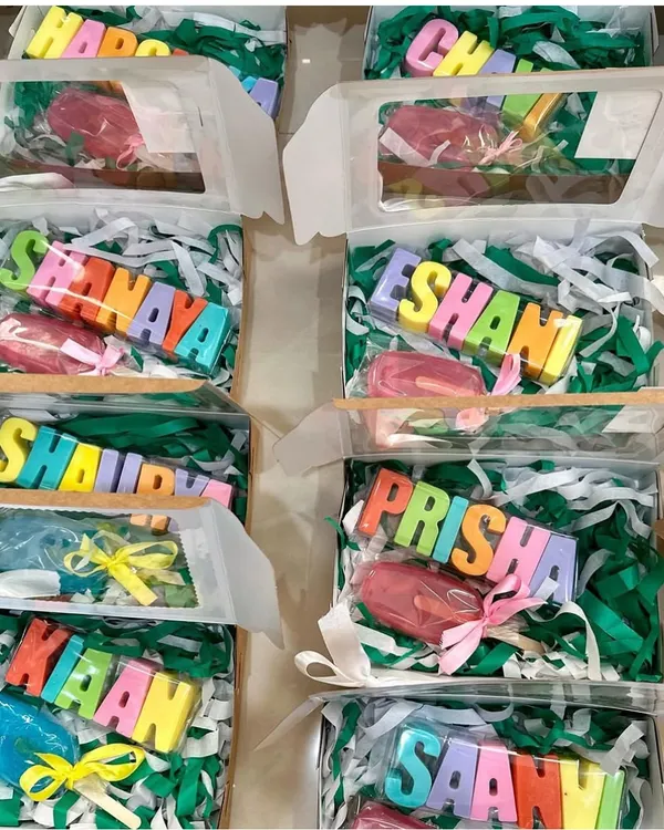 A vibrant display of personalized return gift boxes, each featuring a colorful name soap and a matching popsicle soap. This is a budget-friendly yet impactful way to thank guests at your child's party.