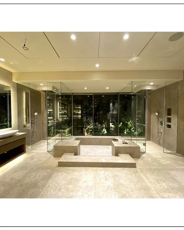 This is the epitome of a spa-inspired bathroom. The central jacuzzi, surrounded by glass, looks out onto a private garden, creating an immersive experience that combines the luxury of a spa with the serenity of nature.