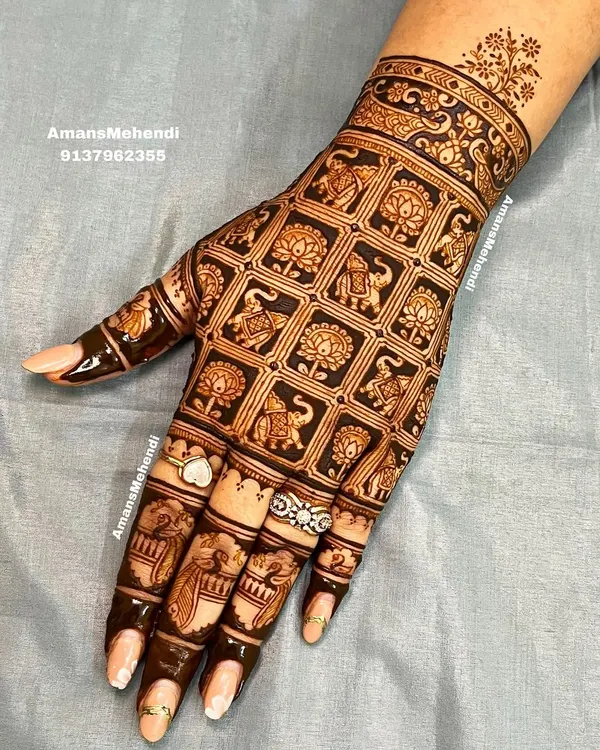 A stunning grid pattern on the back of the hand. Each square is filled with an alternating elephant or lotus motif, creating a design that is both intricate and orderly.