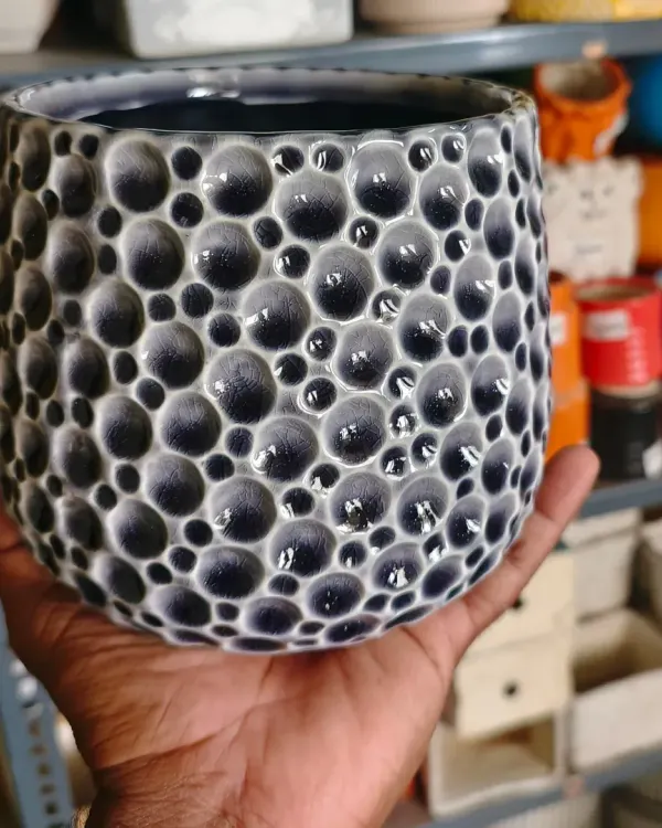 This 6-inch imported ceramic pot features a unique bubble texture in a deep blue-grey glaze. It's a heavy, high-quality planter that adds a touch of sophistication to any indoor plant.