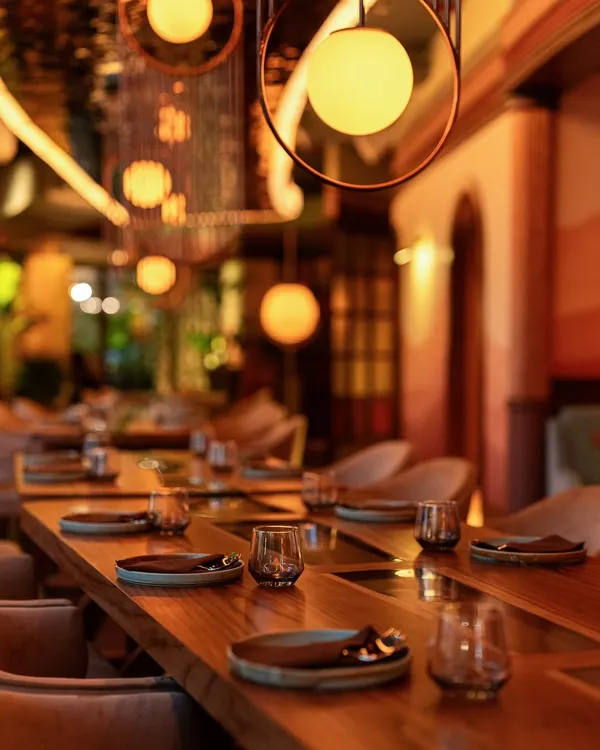The view down our main dining hall in Mumbai, set for an evening of conversation and connection. The long wooden tables and soft, spherical lighting create a warm and inviting atmosphere for large group dinners.