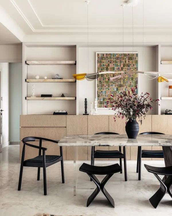Introducing Apartment O2, a home where every corner invites warmth and happiness. The dining area features a stunning marble table with a unique glass and wood base, reflecting the family's creative spirit and love for playful design.