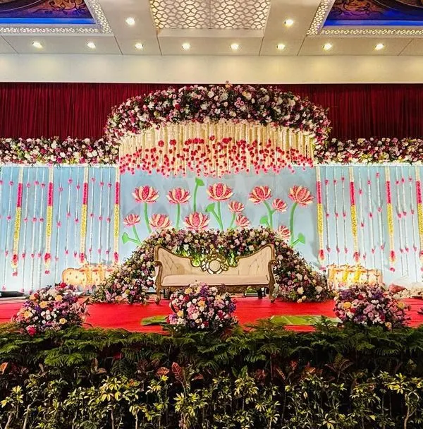 A breathtaking stage for a twin babies' cradle ceremony, designed with symmetrical floral moons and a vibrant lotus theme. This grand setup combines traditional motifs with a lavish floral display, creating a truly memorable backdrop for a special day.