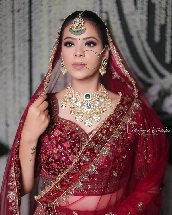 The kind of bridal beauty that turns heads and tells stories. This regal look, with its rich red velvet, intricate jewellery, and confident gaze, is rooted in tradition and designed to be unforgettable.