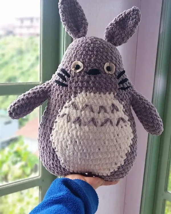A close-up of the finished large Totoro plushie, made with soft, thick yarn for extra cuddliness. The details include his whiskers, grey belly markings, and big, friendly eyes.