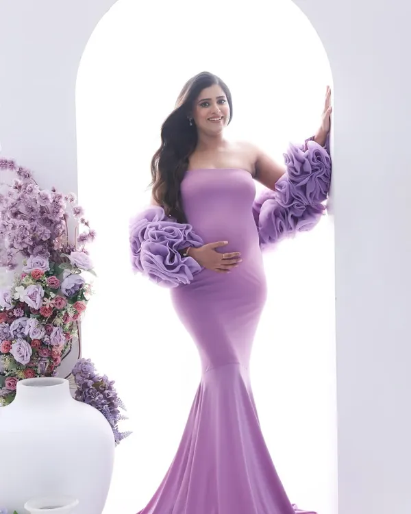 A vision in lavender. This dramatic mermaid gown with ruffled sleeves makes a stunning statement, complemented by the floral arrangement for a touch of fairytale elegance.