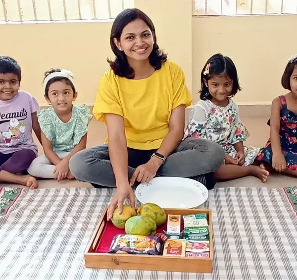 We're all set for our mango cheesecake activity. I guide the children as they get ready to explore ingredients and learn through this exciting fireless cooking project.