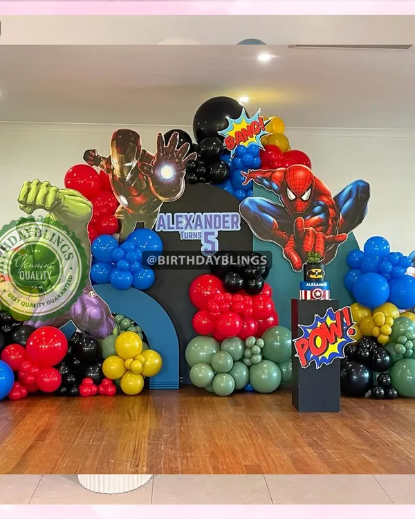 An epic Avengers-themed birthday party, assembling Iron Man, Spider-Man, Captain America, and the Hulk. The setup features a multi-panel city skyline backdrop and balloon colors matching each hero.