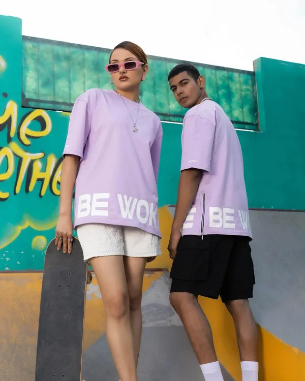 A dynamic shot from a streetwear campaign set in a skate park. The styling combines oversized graphic tees with casual shorts and a skateboard as a prop to create an authentic, urban feel.
