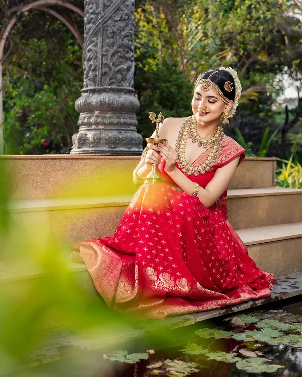 A serene moment from a beautiful photoshoot. The model is wearing a traditional red lehenga with one of my antique gold necklace sets, creating a timeless and elegant look.