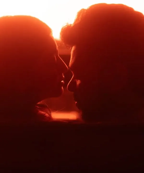 A powerful silhouette of the couple about to kiss, illuminated by a dramatic red light from within a car. This shot is pure cinema, focusing on the anticipation and intensity of the moment.