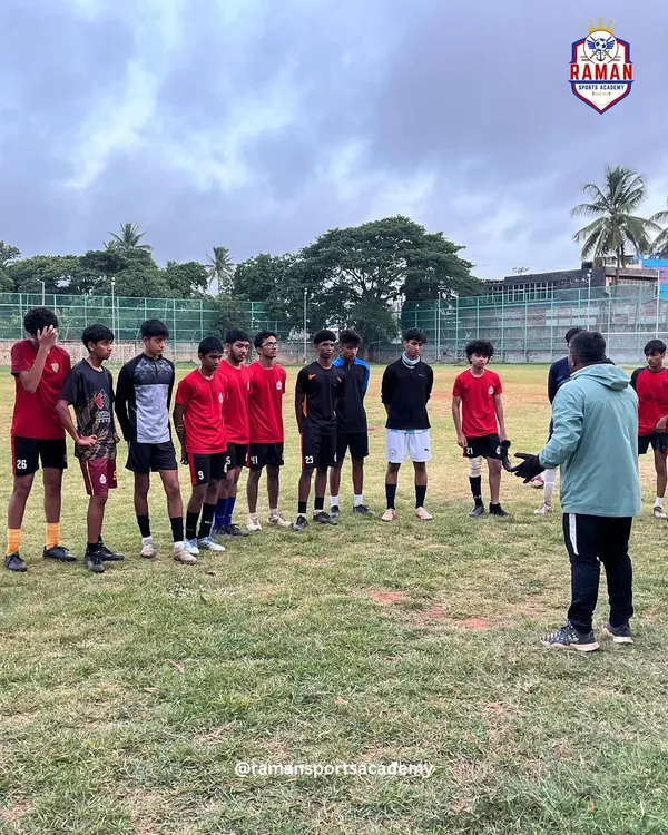 A coach provides tactical instructions to a group of our youth players during a daytime training session on the grass pitch.