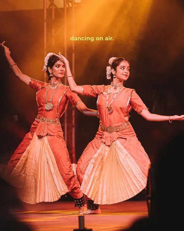 Two classical dancers strike a synchronized pose under warm stage lights. This shot, edited with a cinematic feel, captures the grace and precision of traditional Indian performance art.