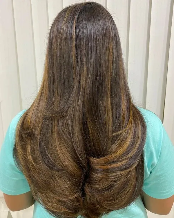 This layered haircut with warm balayage highlights is a perfect example of student work. We teach you how to combine cutting and coloring techniques to create a seamless, professional look.