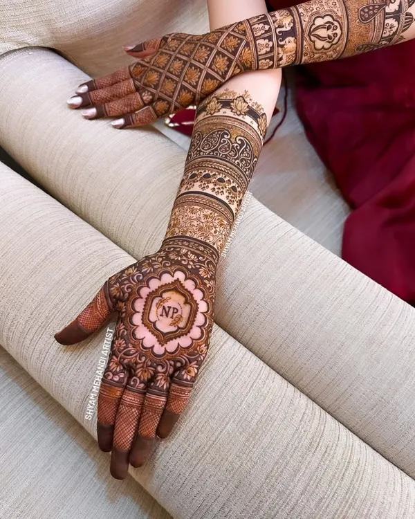 A beautiful full-arm design personalized with the couple's initials "NP" inside a floral mandala on the palm.
