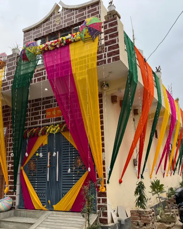 Make your home look festive with our exterior decoration services. Here, we've used long, flowing drapes in auspicious colors like yellow, pink, and green to adorn the front of the house for a wedding celebration.