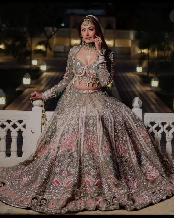 A breathtaking sage green and pink floral lehenga, featuring intricate pearl and thread embroidery on the corset-style blouse. This exclusive designer piece is perfect for a bride looking for a unique, high-fashion statement on her wedding day.