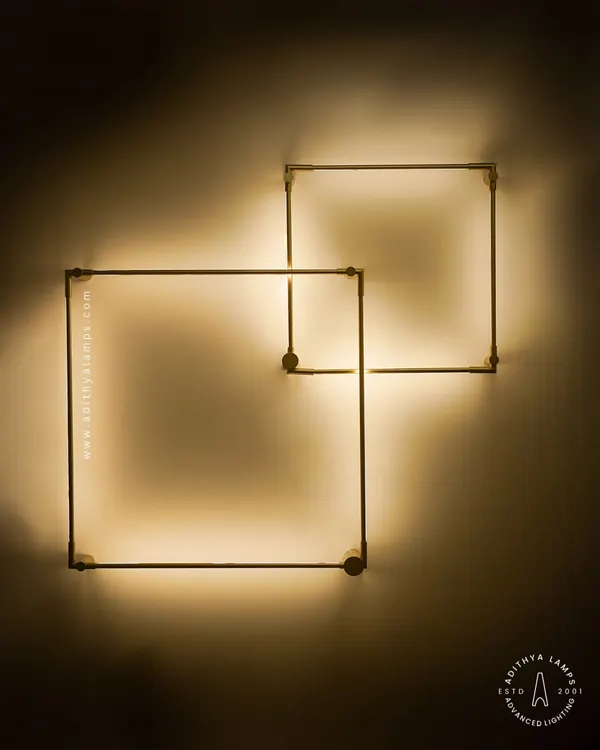 This geometric wall light features two interlocking squares that create a beautiful back-lit glow. It's a minimalist art piece that adds a warm, ambient light and a touch of modern sophistication to any wall.