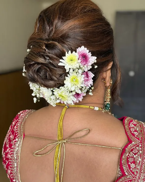 A classic bridal bun adorned with fresh, colorful flowers. This timeless hairstyle adds a touch of elegance and tradition to any bridal look.