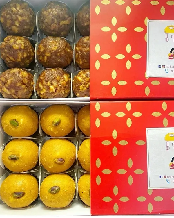 Boxes of our fresh homemade laddoos ready for delivery. This image shows our sugar-free Date and Walnut laddoos alongside our classic Besan Laddoos, packed in festive red boxes.