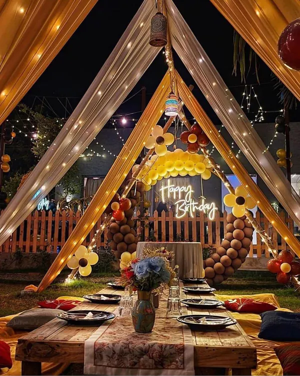 This is a complete view of my intimate cabana dinner setup. It features a low wooden table, colorful cushions for comfortable floor seating, and a beautifully set table, all under a canopy of glowing lights.
