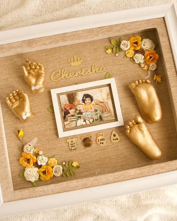 I absolutely loved creating this keepsake for baby Cherisha. The golden casts of her hands and feet are set against a warm, wood-textured background, complete with her photo, birth details, and delicate floral accents. It's a complete story in a single frame.