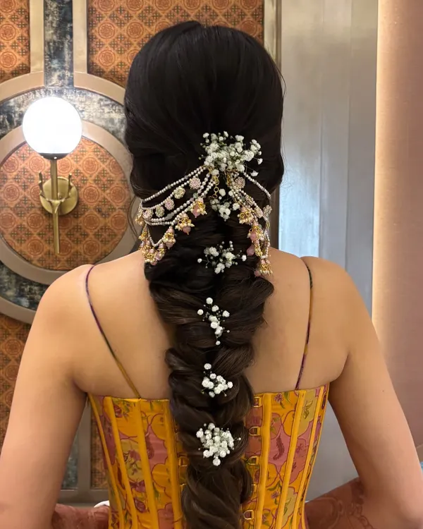This is the kind of bridal braid that makes a statement. I created a thick, voluminous fishtail braid and then adorned it with a beautiful pearl and kundan hair accessory, weaving in delicate baby's breath for a soft, romantic finish. It's a perfect hairstyle for a Mehendi or Sangeet ceremony.