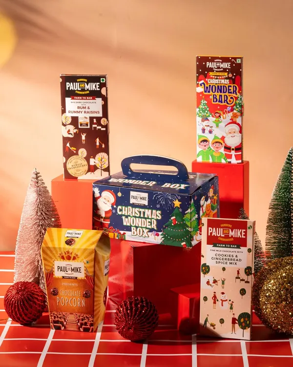 A Christmas-themed product lineup for Paul & Mike chocolates. This shot is styled for a seasonal campaign, showcasing a gift box and multiple products.