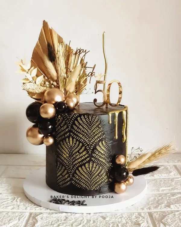 There's something mysteriously captivating about black and gold. This 50th birthday cake features a bold black design with a gold leaf stencil, drip effect, and a cascade of black and gold spheres.