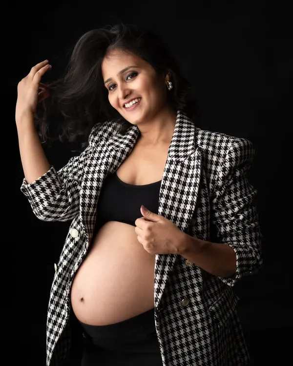 Who says maternity can't be chic? This mom-to-be looks amazing in a trendy houndstooth blazer and a crop top that proudly shows off her baby bump. A modern and stylish look for a studio portrait.