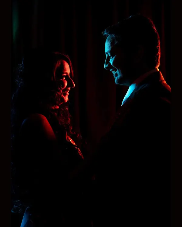 A silhouette portrait of the couple, using dramatic red and blue backlighting to create an intimate and moody reception shot.