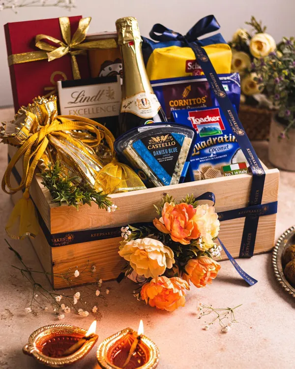 This "Utsav" style hamper is the epitome of luxury corporate gifting. It features a curated selection of premium champagne, Danish blue cheese, and gourmet snacks presented in a keepsake wooden crate, finished with fresh flowers and a branded ribbon.