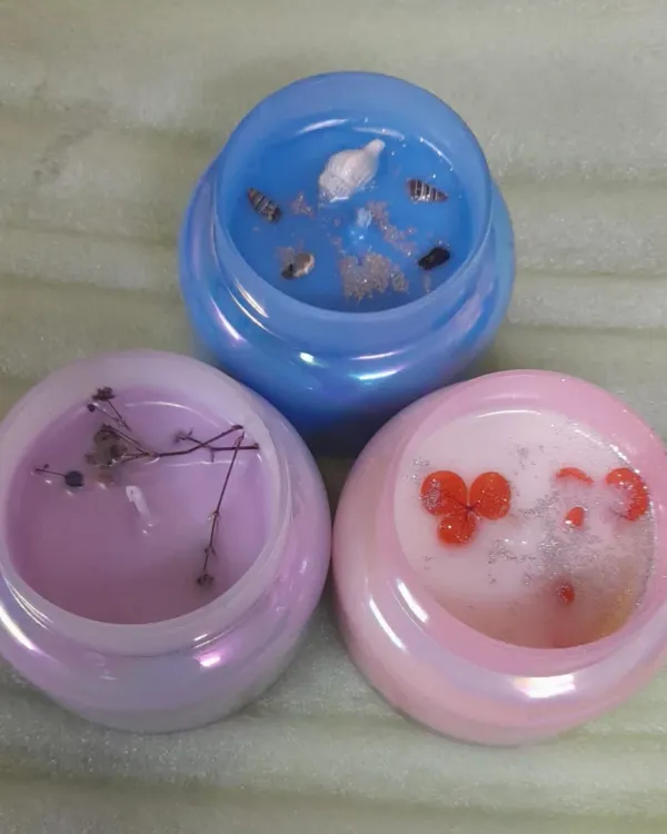 Soft glow, gentle vibes. These iridescent jars are filled with pastel-colored wax and decorated with natural elements like dried flowers and seashells.