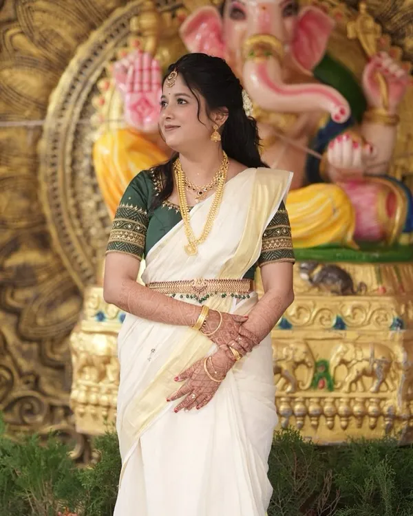 Sneha's elegant look for her Varapooje ceremony. The classic Kerala Kasavu saree is paired with subtle makeup and traditional gold jewelry.