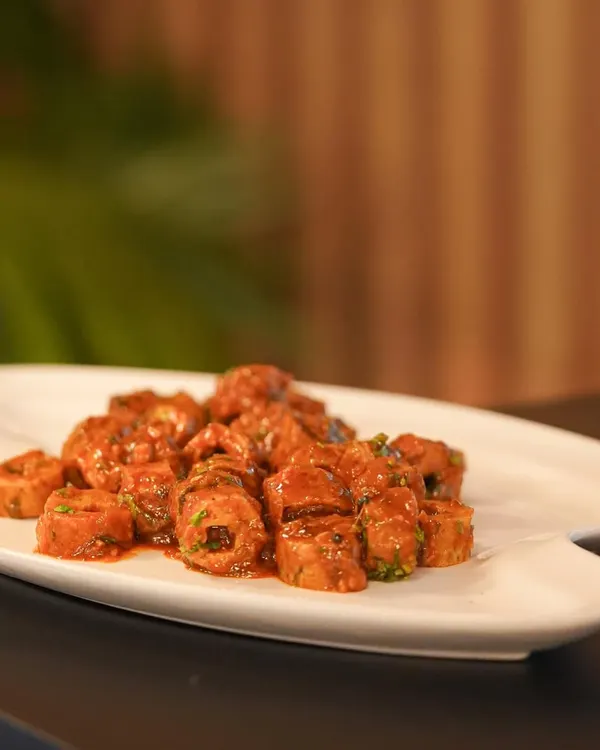 A platter of saucy, sliced seekh kebabs, ready to be served. This shot captures the final moments before a dish goes out to a guest at an event.