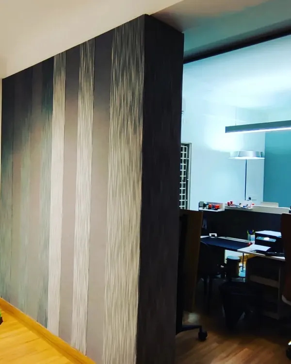 This is a finished acoustic fabric panel wall. The striped pattern adds a decorative element while the material itself effectively absorbs sound, making the adjacent office space quieter.