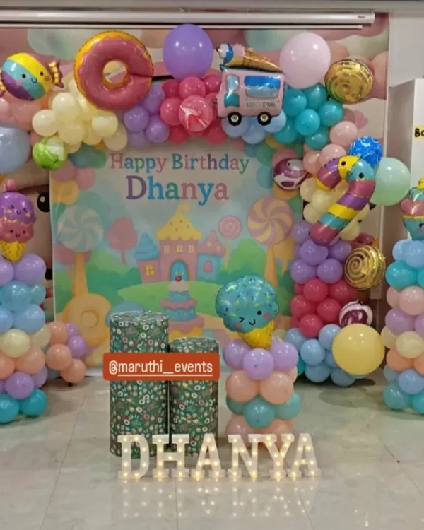 A delicious-looking Candyland theme! This sweet setup features a pastel backdrop, balloon columns topped with ice cream cone balloons, and a donut foil balloon on the arch.