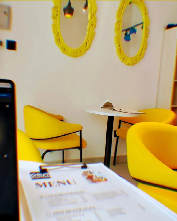 A glimpse of the vibrant and cozy interior at our Sector 132 cafe. The bright yellow chairs and modern decor create a welcoming space for you to relax or work.