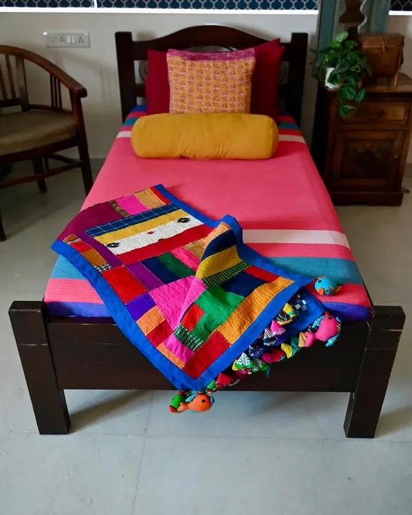A full view of the improv quilt, a vibrant tapestry made entirely from fabric scraps and studio waste. The playful fish-shaped tassels are also crafted from leftover bits of cloth.